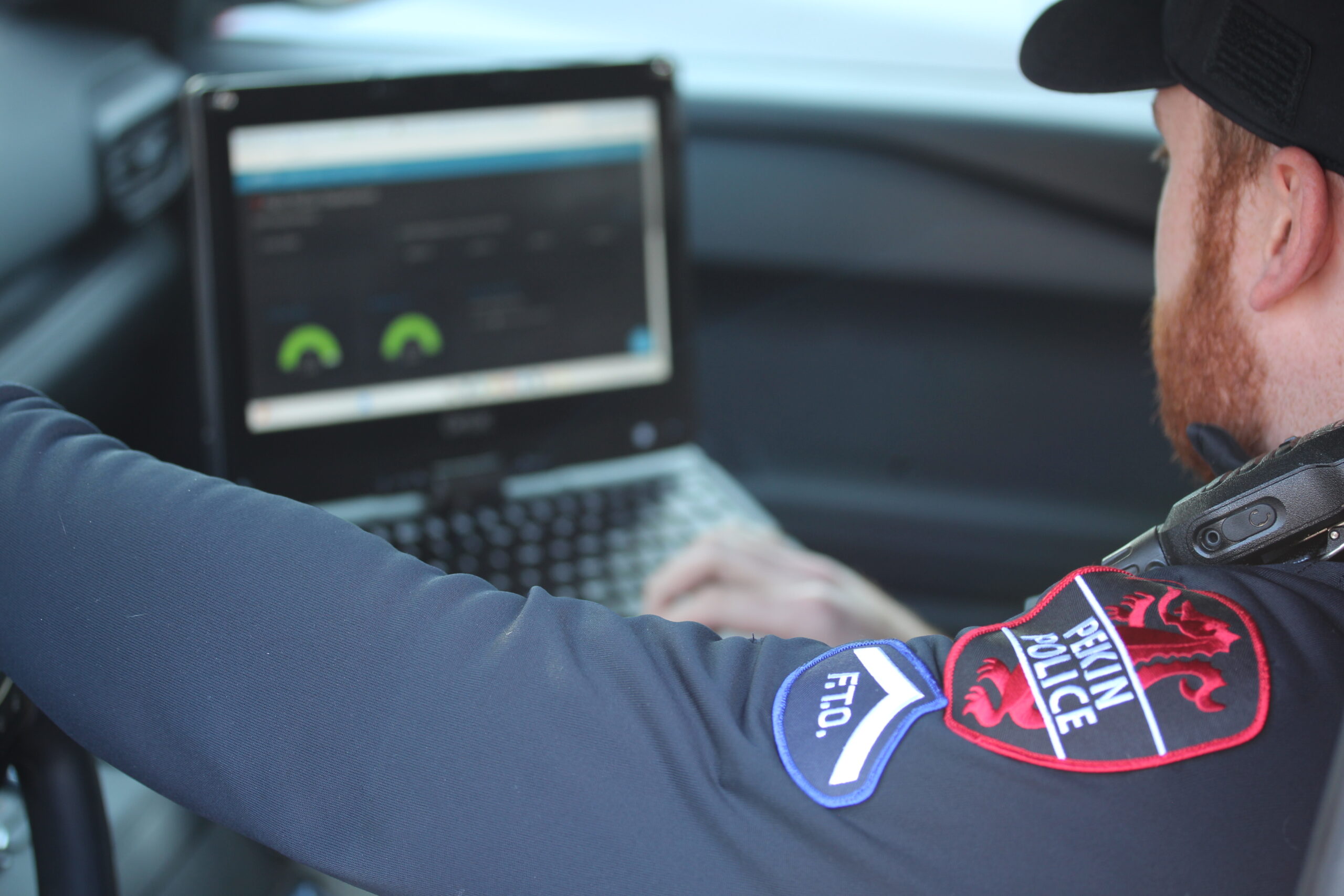 Field Training Officer sitting in vehicle looking at computer screen